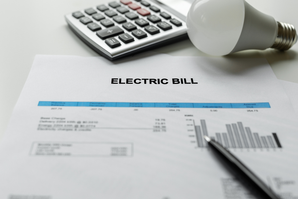 Electric bill on a table with a calculator and lightbulb beside it