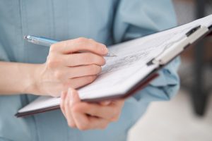 close up of a hand taking notes on a clip board