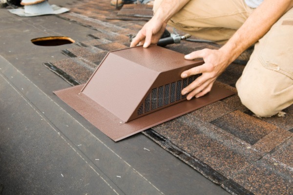 A person of a roof installing a new roof vent
