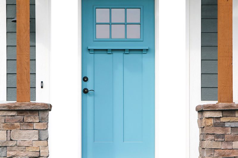 A photo of a light blue new front entry door on a home with stone pillars on the front porch.
