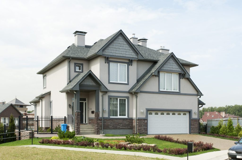 Contemporary suburban home with patterned gray shingles and decorative gables, highlighting modern roofing ideas with architectural charm.