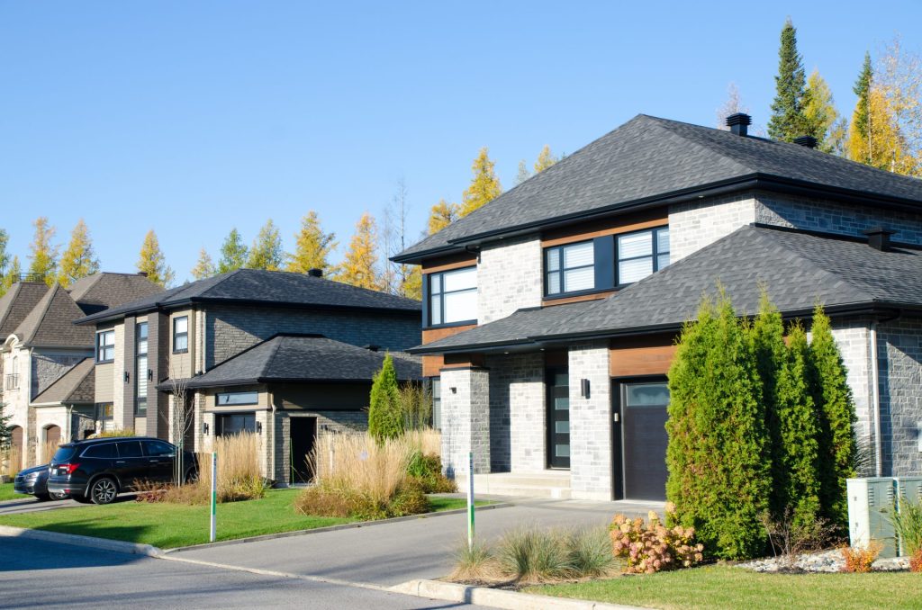 Modern suburban neighborhood with homes featuring dark roof colour trends for 2025 against a clear blue sky.